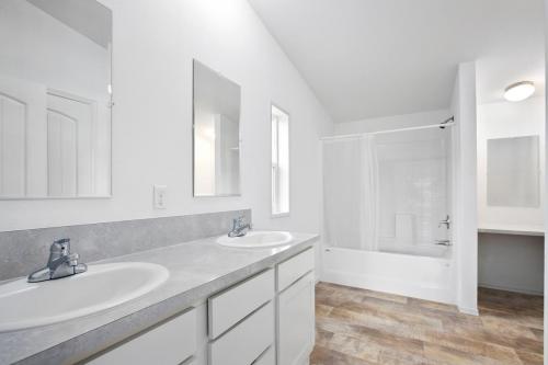 A white bathroom with two sinks and a shower.