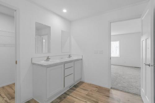 A white bathroom with wood floors and a sink.